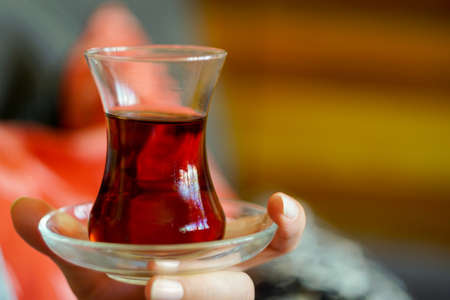 Woman holding thin belly glass of turkish tea in hand close up viewの写真素材