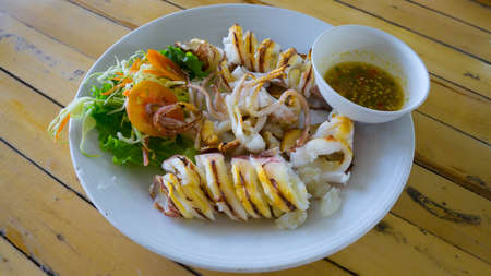 Grilled squid with salad and seafood sauce on white plate