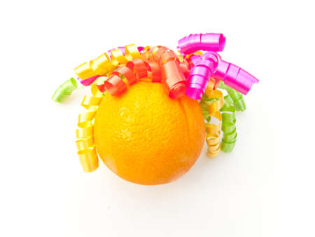 A ripe orange with colourful, curly gift wrapping decoration. On white background.の写真素材