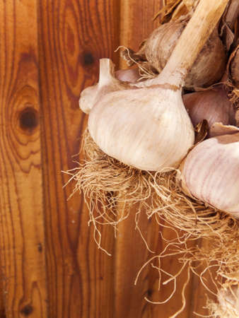 A bunch of garlic hanging, with brown wood background.の写真素材