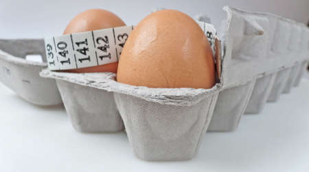 Two eggs in a grey carton with tape measure, selective focus. Health concept.の写真素材