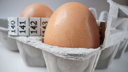 Brown eggs in a grey carton with measuring tape. Selective focus. Health concept.の写真素材