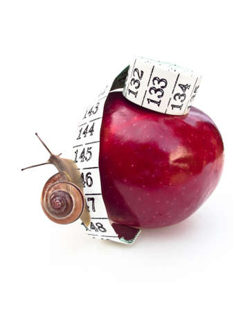 A snail climbing up an apple by a tape measure. Health concept.の写真素材