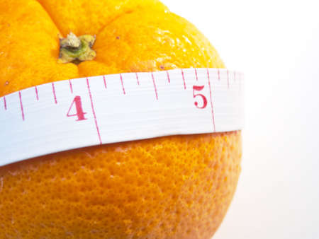 A ripe orange with a measuring tape around it, with selective focus.の写真素材