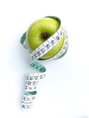 A granny smith apple surrounded by a measuring tape, isolated on white. の写真素材