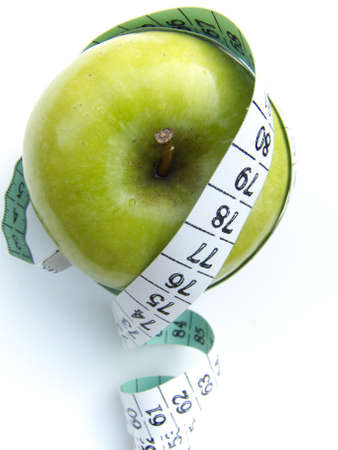A granny smith apple surrounded by a measuring tape, isolated on white. の写真素材