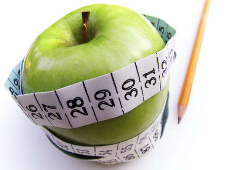 A granny smith apple surrounded by a measuring tape, isolated on white. の写真素材