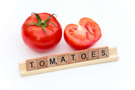 letters writing the word tomatoes with two ripe tomatoes behind it.の写真素材