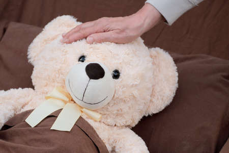 Tending to sick patient (plush bear) lying in bed.の写真素材