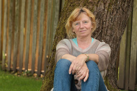 Mature woman resting against treeの写真素材