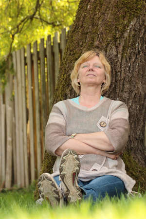 Mature woman resting against tree 2の写真素材