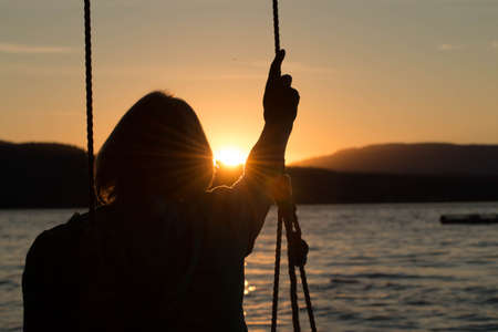 Mature woman on swing at sunsetの写真素材