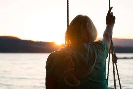 Mature woman facing sunset on beachの写真素材