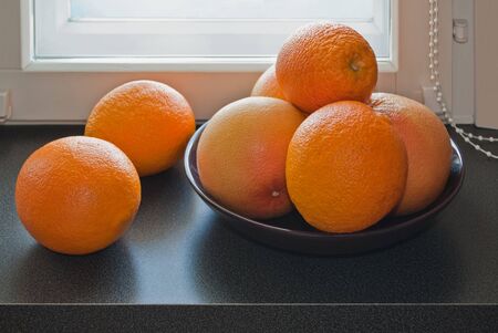 Fresh oranges and grapefruit in the cup on the windowsill の写真素材