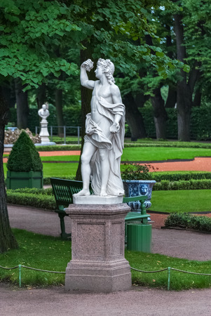 Marble sculpture on a granite pedestal in the Summer garden on a green background lattice.のeditorial素材