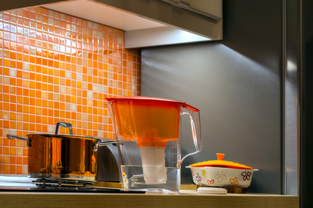 The interior of the kitchen is in orange tones with a saucepan and a water filter.の写真素材