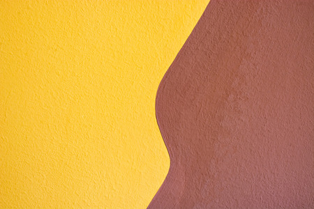 A fragment of a wall plastered in two colors, yellow and brown, for use as a background.の写真素材