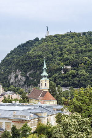 View of Gellert Hill and the Statue of Liberty in Budapest. In the foreground is the church tower with a clock.のeditorial素材