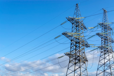 Two supports of high-voltage transmission line with electric power wires on the blue sky background.
