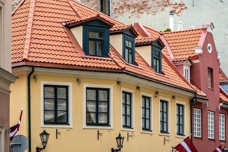 House with yellow walls, with attics on the roof of red tiles in the old part of Riga.
