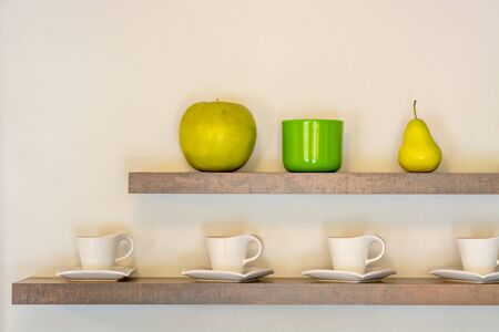 Interior with two shelves with white cups and fruit on beige wall background.の写真素材