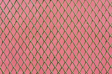 Image of metal grid on pink wall background for use as abstract background.の写真素材