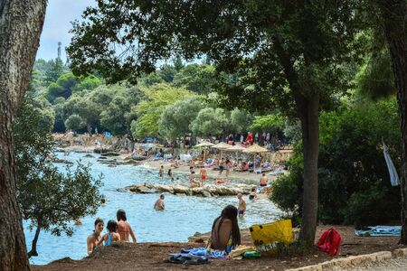 Rovinj, Croatia, August 23: Citizens and tourists sunbathe on the Mulini beach and swim in the clear waters of the Adriatic on a bright sunny day, August 23, 2019.のeditorial素材