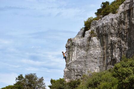 Rovinj, Croatia, August 22: a Tourist climber conquers sheer rock cliffs during a training session in the Zlatni Rt forest Park, August 22, 2019.のeditorial素材