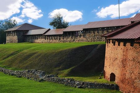 Fragment of an old fortress wall made of stone on an earthen rampart covered with green grass in the...