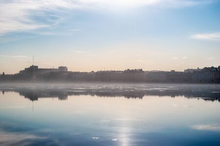 Neva river embankment in a haze of fog in the early spring morning in the city of Saint Petersburg.