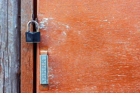 Old padlock iron lock on an old door with peeling paint.