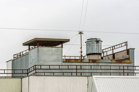 Technical superstructures on the roof of a residential building with wires against a gray sky on a cloudy day.の写真素材