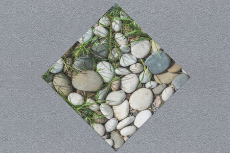 Composite abstract gray background on a plastered wall with a square insert of smooth stones of...