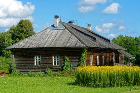 Wooden log house covered with ivy, with a wooden roof and brick chimneys.のeditorial素材