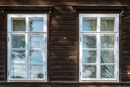 Two rectangular windows with a visor and white frames on a wooden wall in a log house. From the Windows of the world series.の写真素材