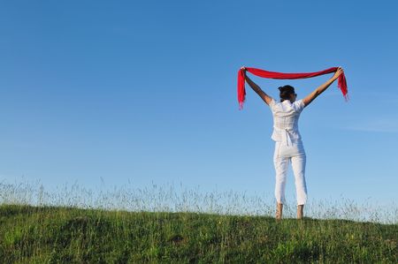 beautiful young and healthy woman run and jump on meadow at sunny day with red scarfの写真素材