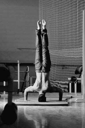 Young man performing  handstand in fitness studio. rear, back perspective.