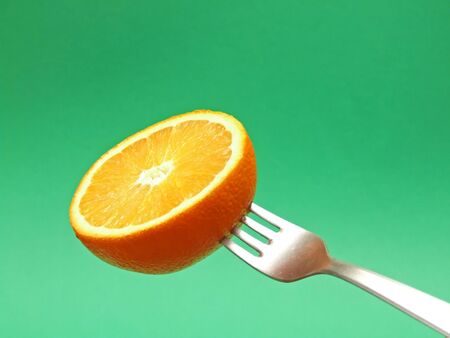 orange on fork with green backgroundの写真素材