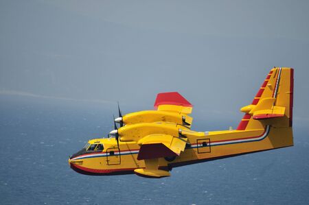 Airplane on sea taking water to drop over fireの写真素材