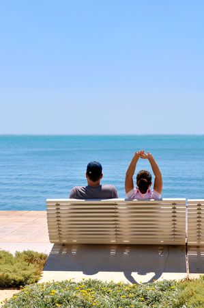 Happy young couple sitting on the beach relaxingの写真素材