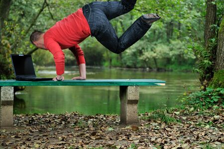 young businessman jump over edge with laptop and green nature in background