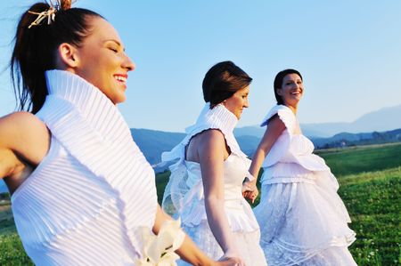 group of bride run on meadow at sunset after wedding partyの写真素材