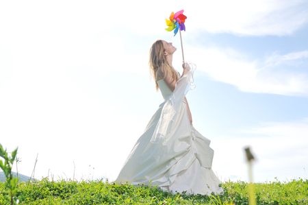 happy young beautiful bride after wedding ceremony event have fun outdoor on meadow at sunset with windmill toy and representing smart energy の写真素材