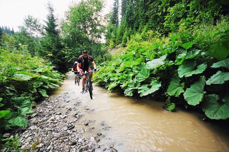 young man drive mountain bike over water riverの写真素材