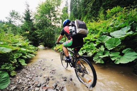 young man drive mountain bike over water riverの写真素材