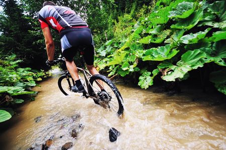 young man drive mountain bike over water riverの写真素材