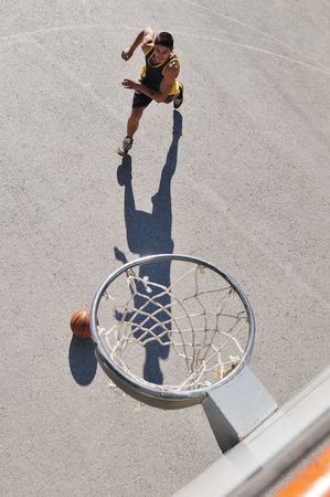 gorup of young boys who playing basketball outdoor on street with long shadows and bird view...