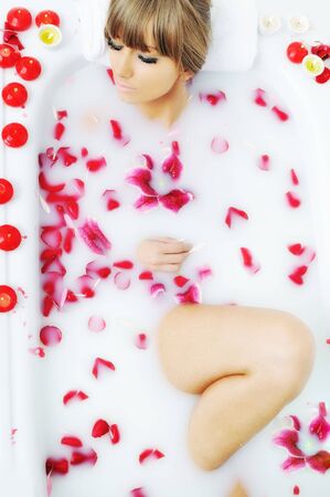 woman beauty spa and wellness treathment with red flower petals in bath