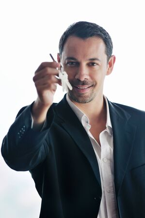 young business man isolated on white holding new home keys and representing sucess in real estate...