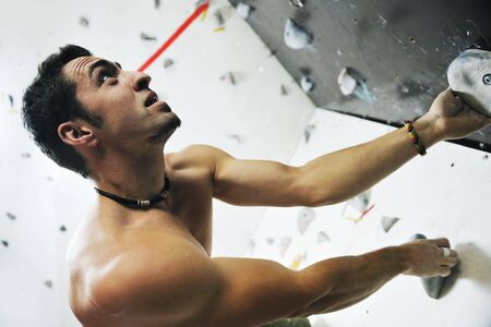young and fit man exercise free mountain climbing on indoor practice wallの写真素材